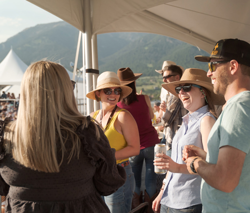 People standing together holding beers wearing hat sand sunglasses