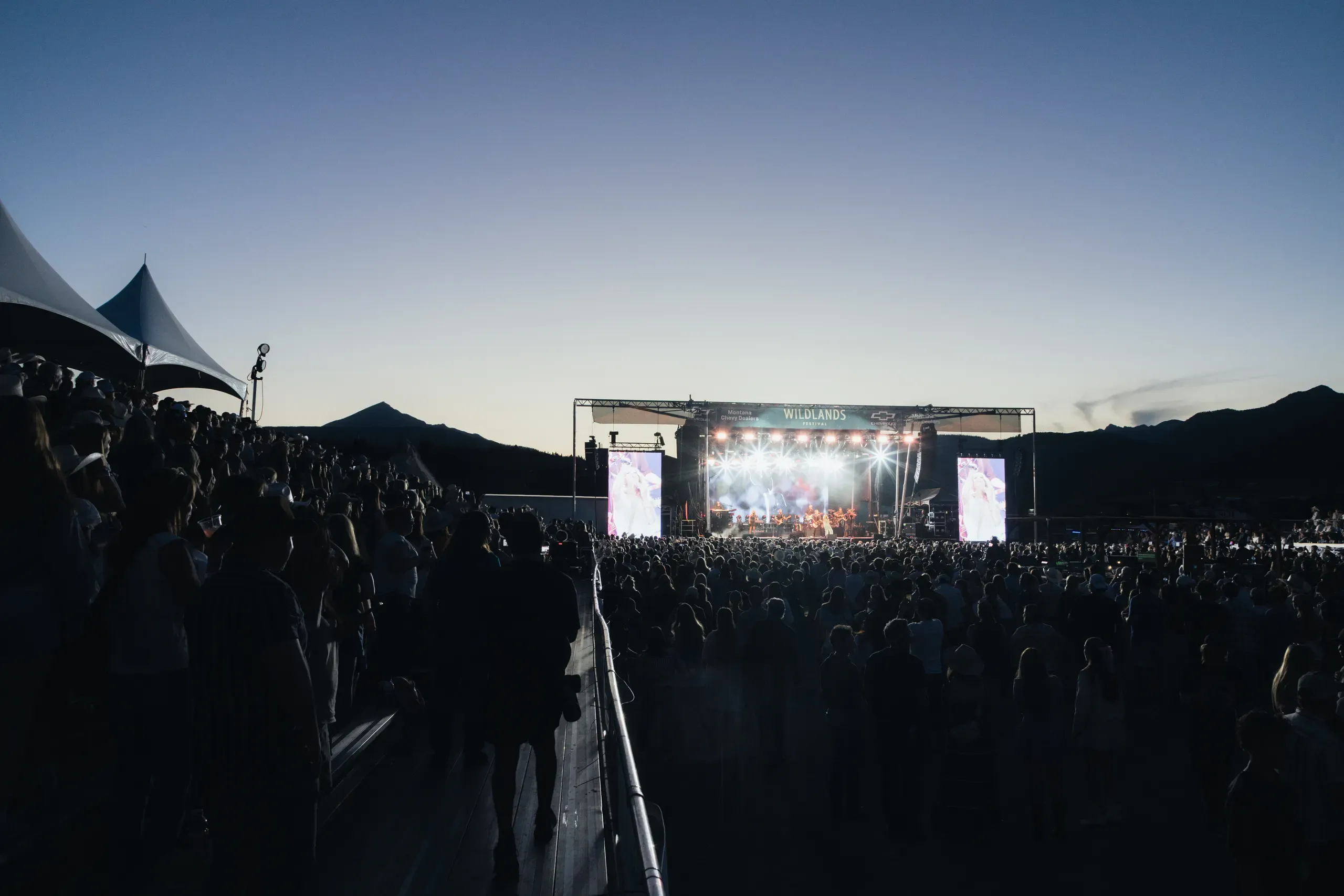 The Wildlands stage at dusk with a full crowd watching beneath the mountain ridge.