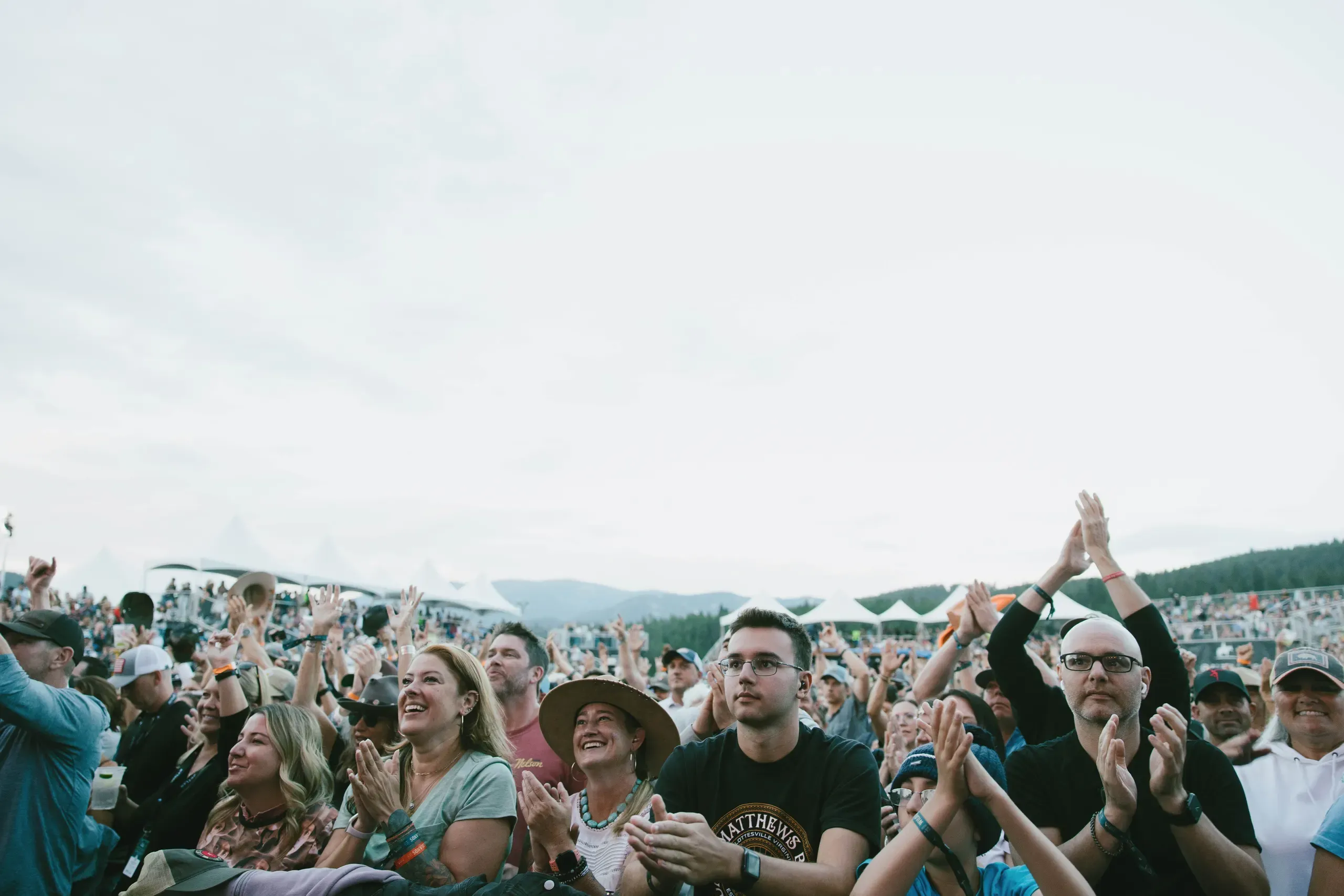 Concertgoers cheering and watching a performance near the front of the stage.