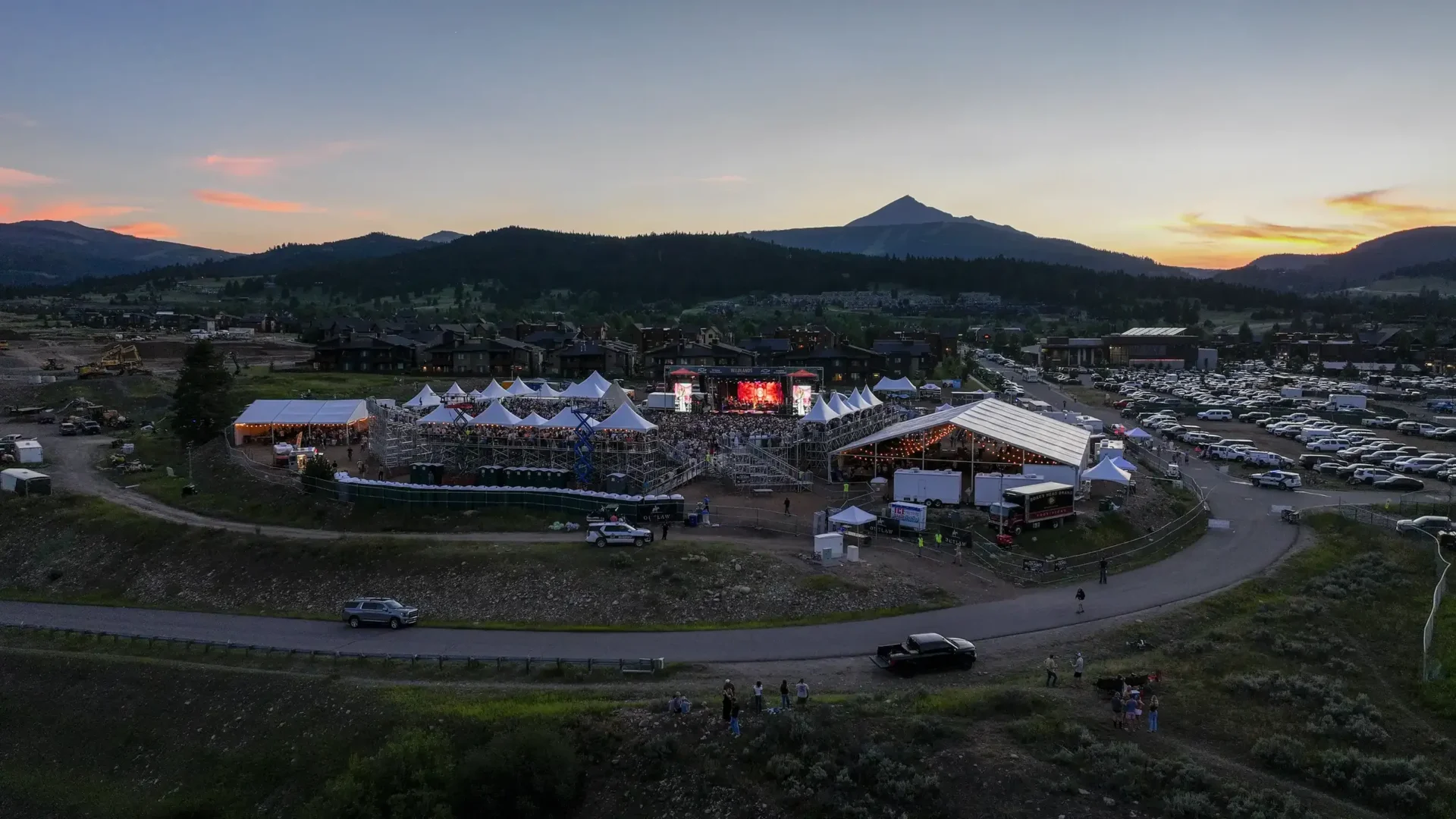 Aerial view of the concert grounds, tents, and surrounding mountains at sunset.