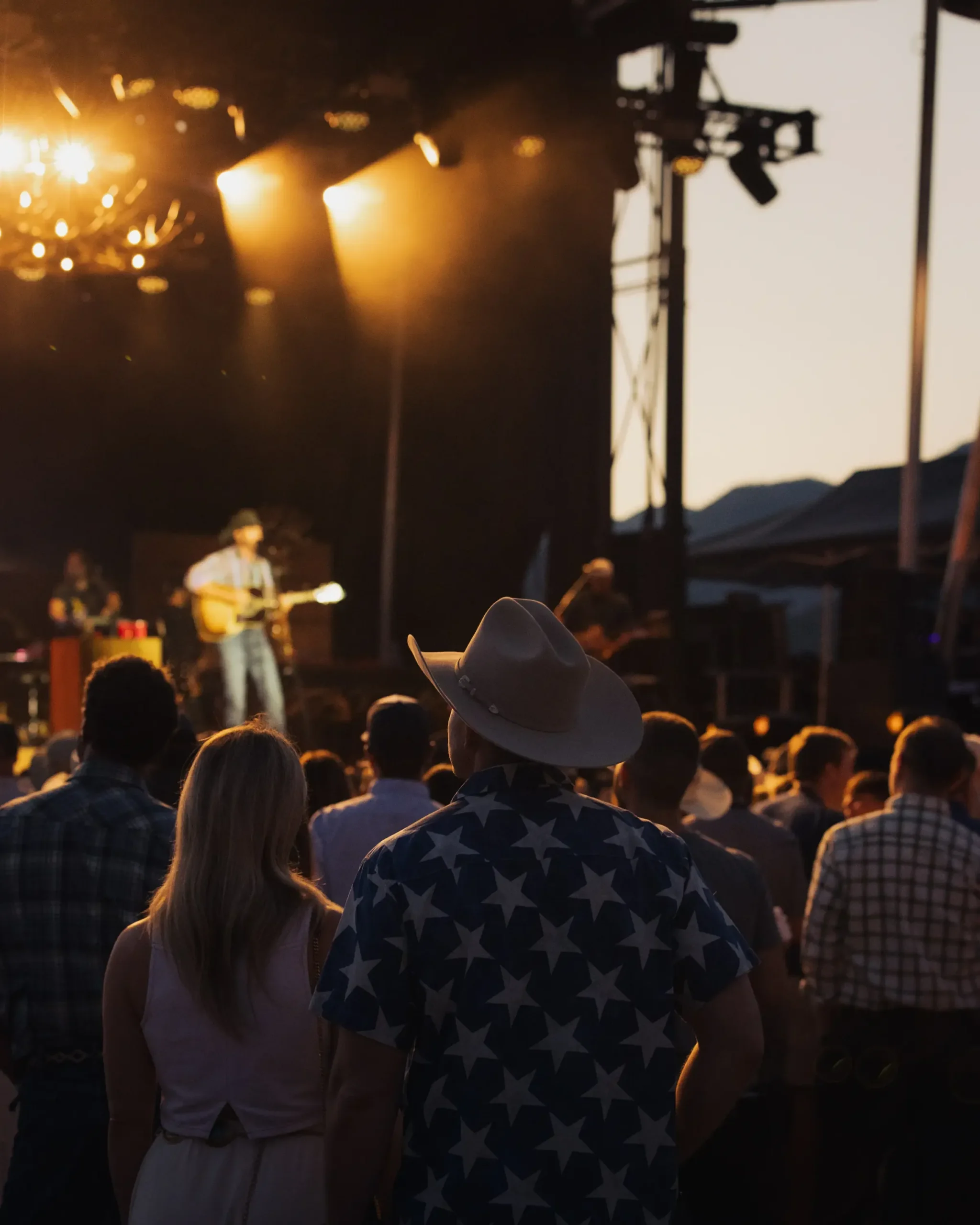 Concertgoers watching an evening performance beneath warm stage lighting.