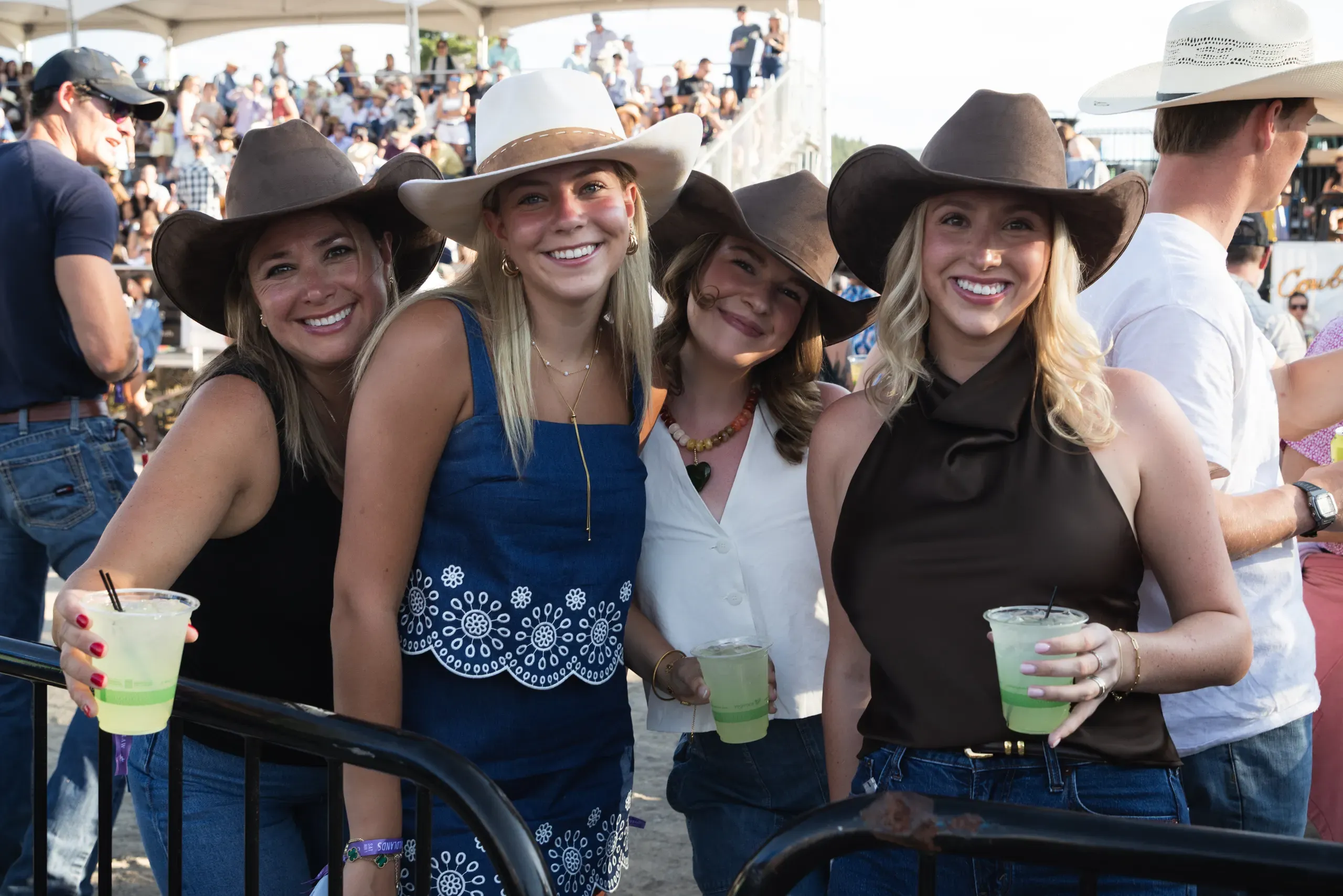 A group of friends in cowboy hats posing together in the crowd.