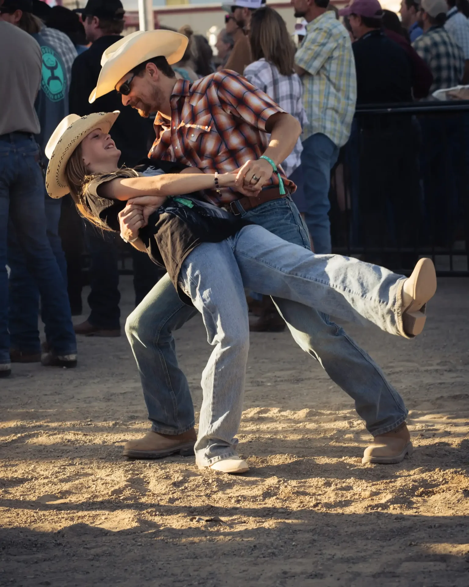 Two concertgoers dancing together on the grass.
