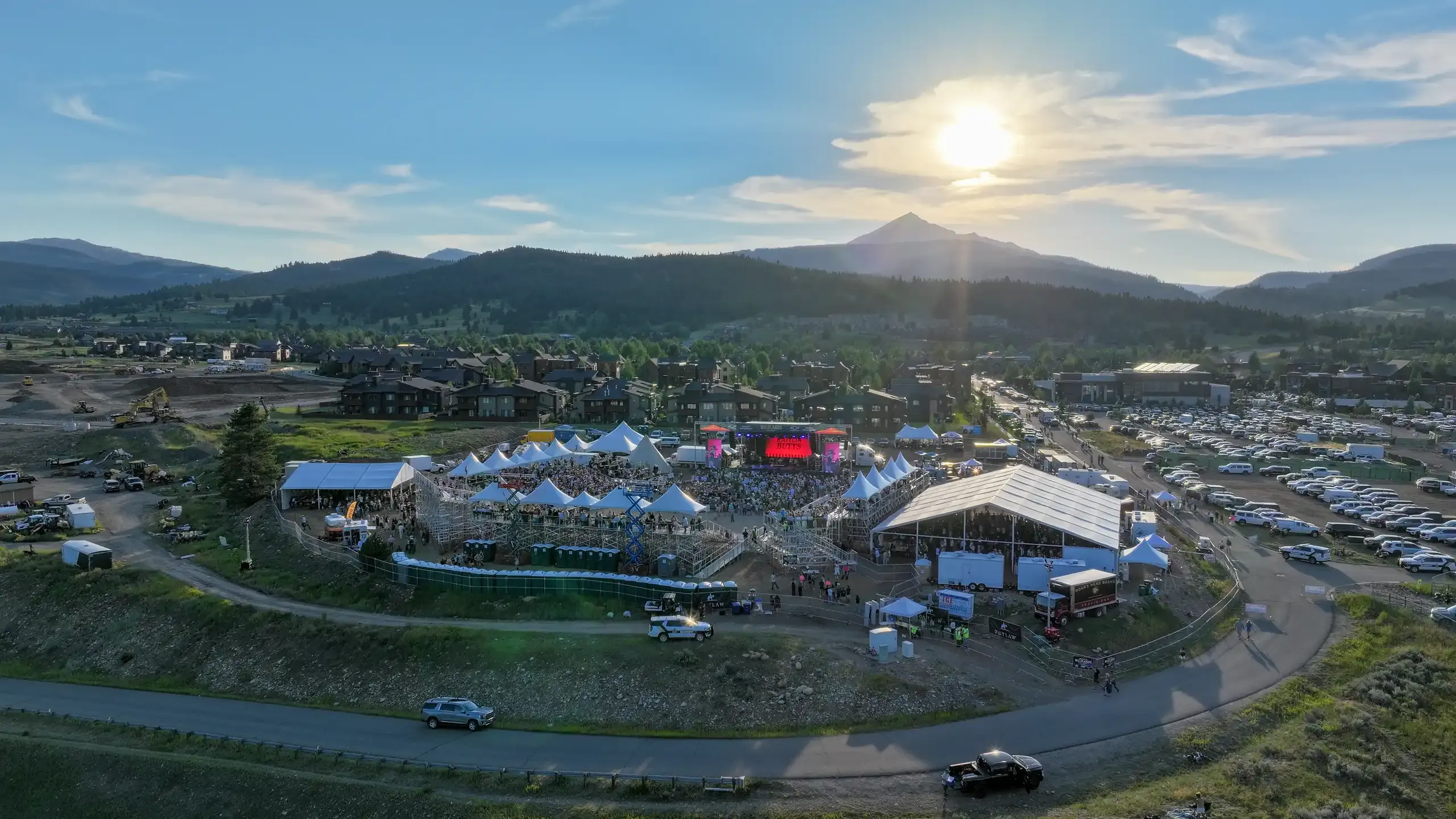 Aerial view of the concert grounds with sunlight breaking over the mountains.