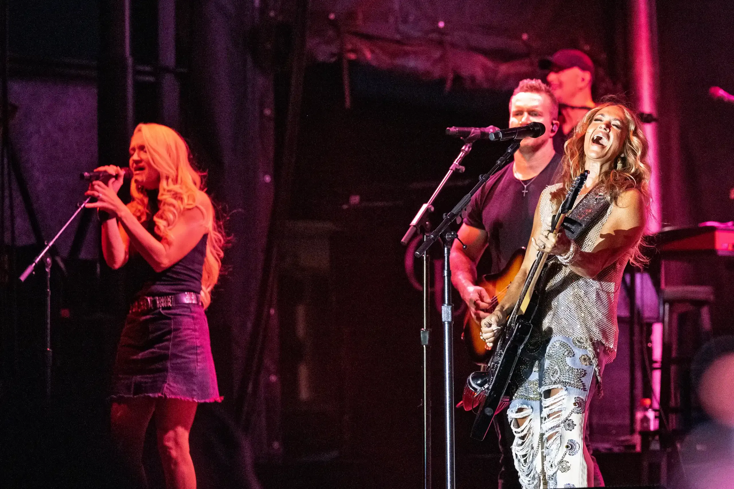 A singer and guitarist sharing a microphone during a performance.